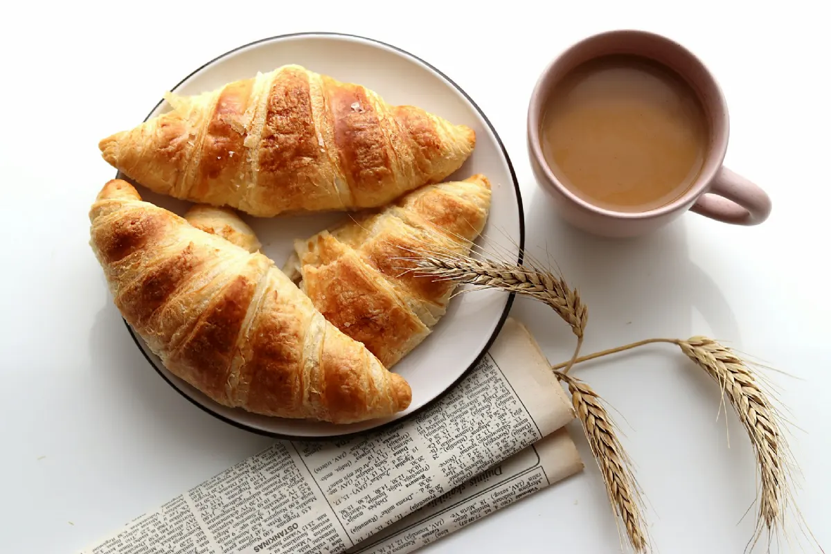 Croissant dorado con corte transversal mostrando el hojaldre
